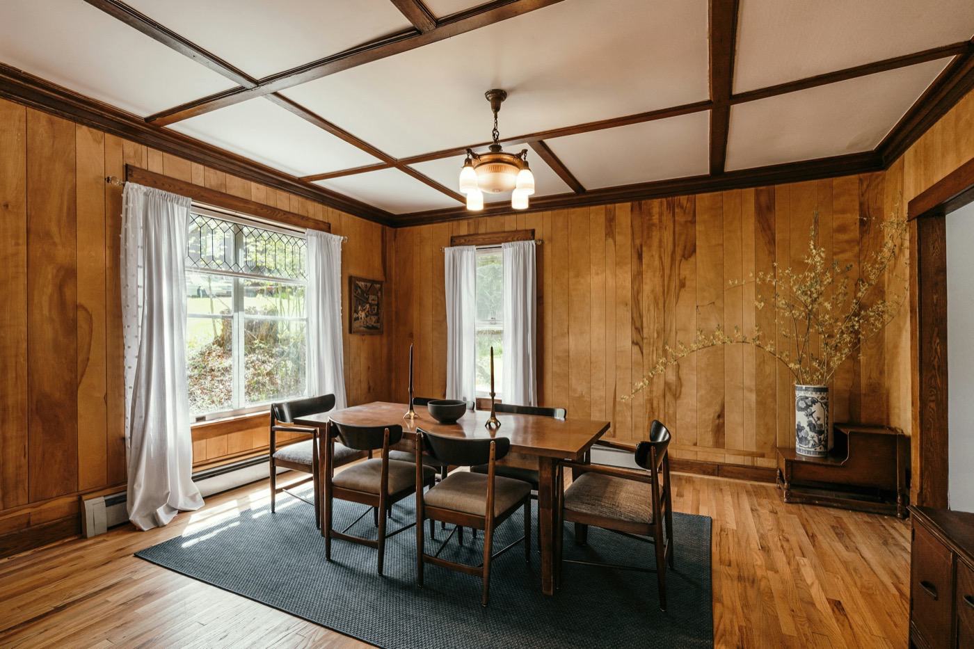 Sunny wood-panelled breakfast room with a small table by the windows