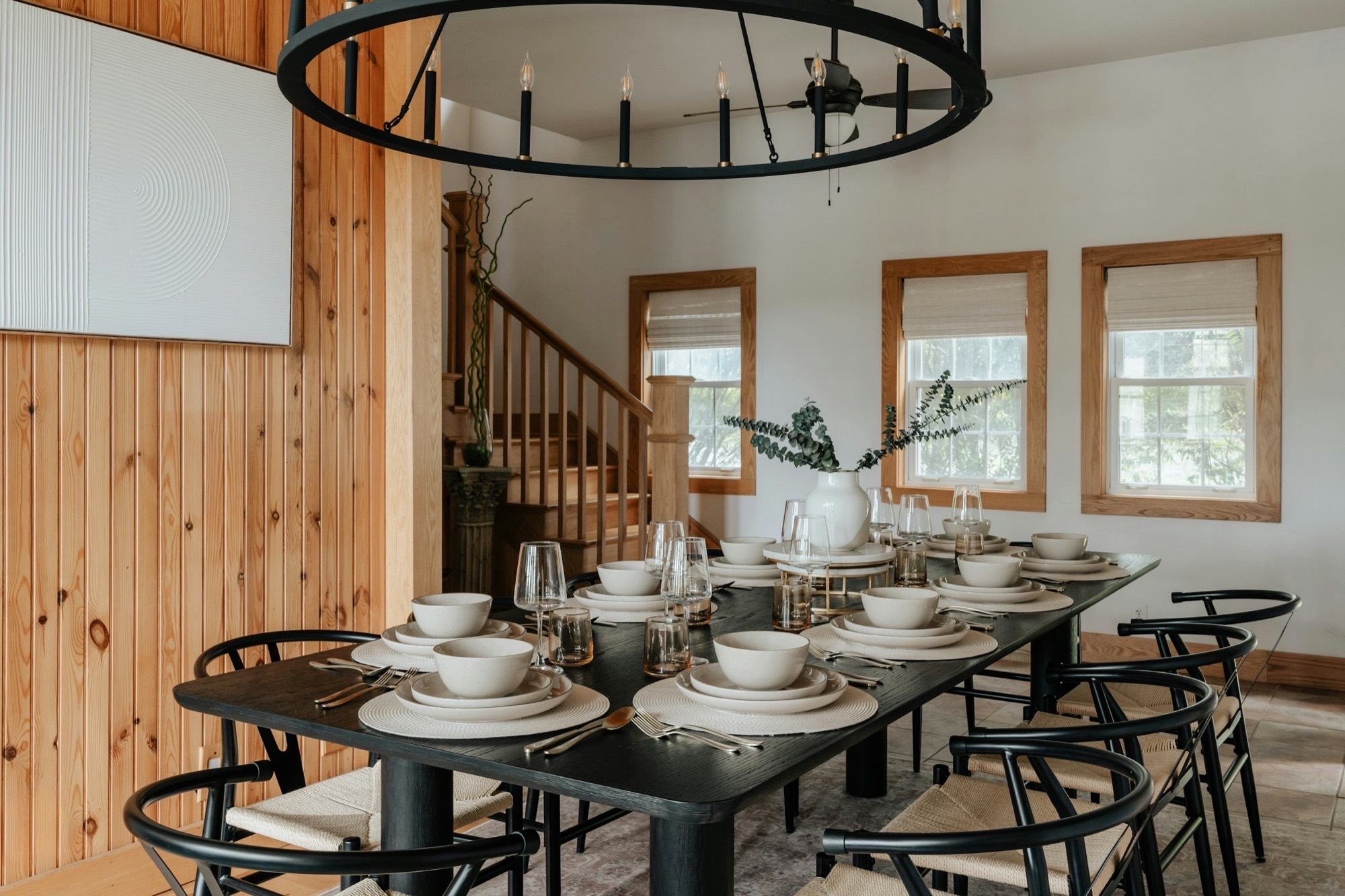 Pine-panelled dining room with a long table set for dinner under an iron chandelier